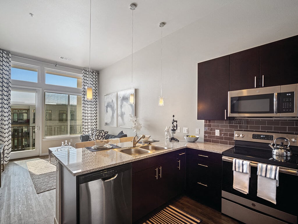 A modern kitchen overlooking the living room at the Douglas Apartments in Denver, Colorado.